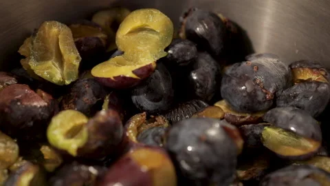 Halved pitted fresh plums falling into the pot Stock Footage 141295310