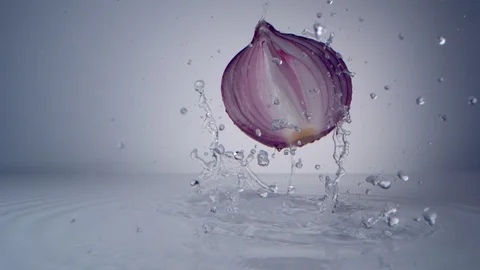 Halved red onion falling on water surface. Slow Motion. Video stock 128770618