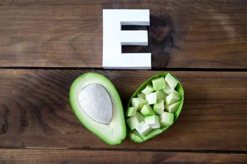 Halves of avocado and letter E on wooden background, top view, Stock Photos