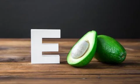 Halves of avocado and letter E on wooden background, top view, Stock Photos