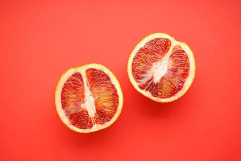 Halves of blood oranges on a red background, flat lay. Stock Photos
