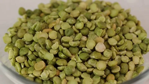 Halves of dried green peas fall in a glass transparent bowl Stock Footage 123149509