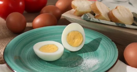 Halves of an egg on a plate. Boiled chicken eggs with bread and tomatoes. Stock Footage 242491315