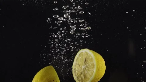 Halves of lemon falling under water with splash isolated over black background Stock Footage 293086087