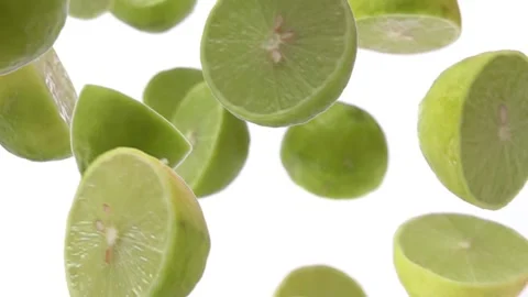 Halves of limes are falling down on the white background in super slow motion Stock Footage 213880870