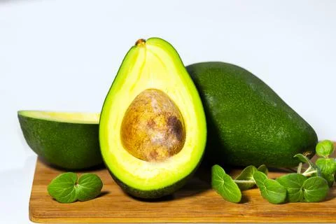 Halves of Ripe Avocado and micro green on wooden board served on table Stock Photos