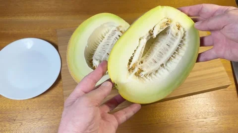 Halves of ripe yellow melon with seeds on cutting board Stock Footage 320257471