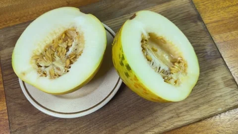 Halves of small yellow melon with seeds on cutting board Stock Footage 320256360