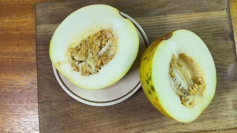 Halves of small yellow melon with seeds on cutting board Stock Footage 320256526