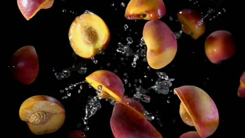 Halves of a wet peach are bouncing in splashes of water on a black background Stock Footage 148871072