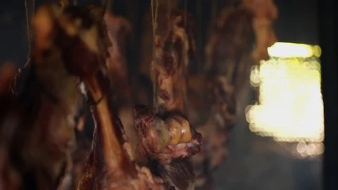 Ham and bacon hanging and drying in smokehouse on traditional way on blue smoke. Stock Footage 121476983