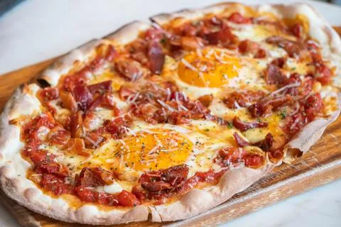 Ham and Eggs Breakfast style pizza on wooden platter Stock Photos