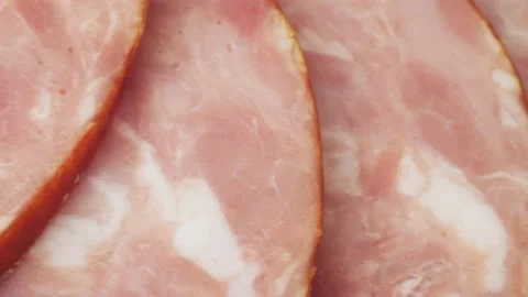 Ham cut into thin slices close-up. Sliced sausage is laid out in a semicircle Stock Footage 220085535