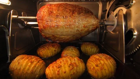 Ham or beef roast. Cooking meat on rotisserie with potatoes. cu B Stock Footage 102139928