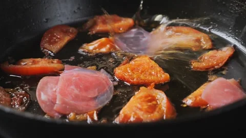 Ham is placed in a frying pan with fried tomatoes and onions. Medium shot. Stock Footage 282735945