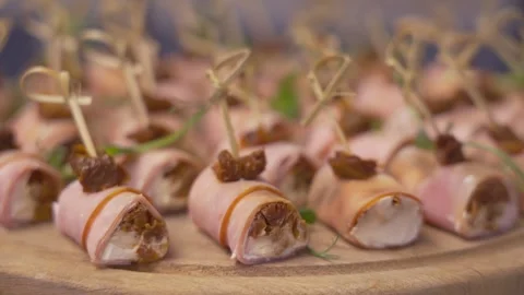 Ham rolls with cheese and dried tomatoes on wooden platter Stock Footage 314856912