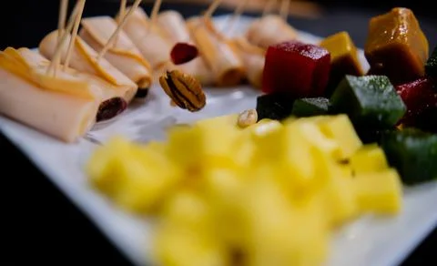 Ham rolls, fruit paste, cheese cubes, and nuts on white plate Stock-Fotos