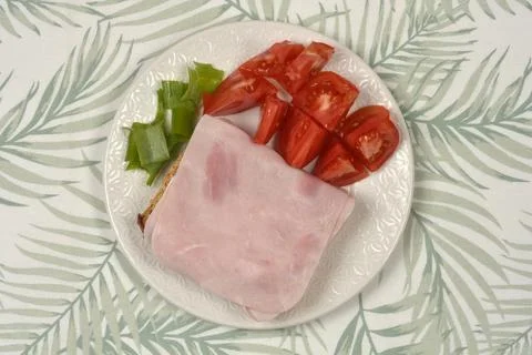 Ham sandwich with tomatoes and spring onions on a plate Stock Photos