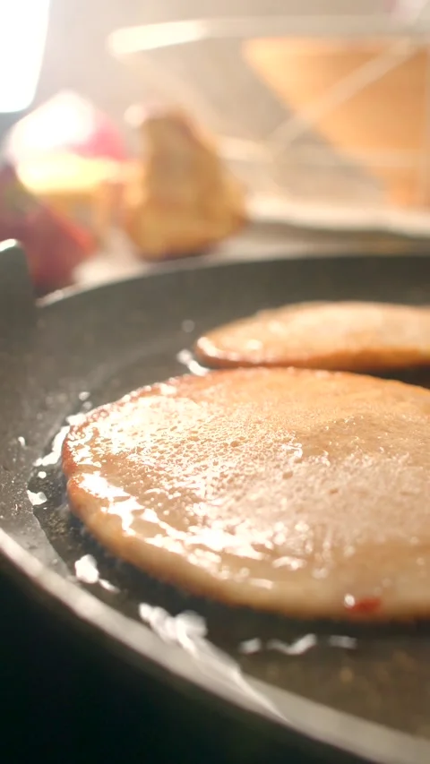 Ham sizzles in a pan, pancakes bubble, showcasing the joy of cooking Stock Footage 314346462
