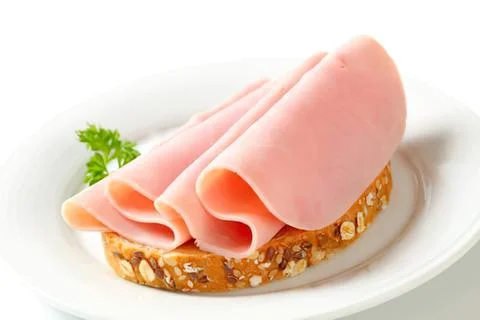 Ham slices on seeded bread with parsley garnish Stock Photos