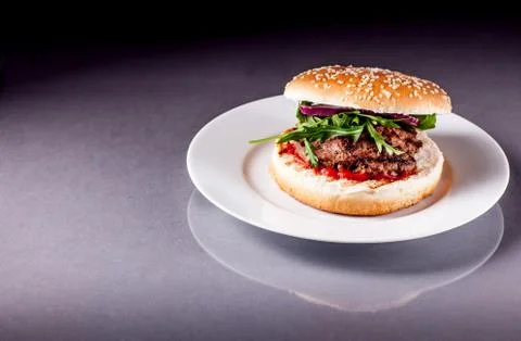 Hamburger with arugula on grey surface Stock Photos