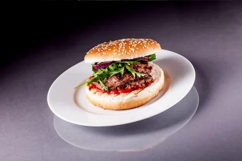 Hamburger with arugula on grey surface Stock Photos