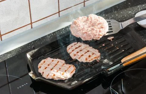 Hamburger being cooked on the griddle Stock Photos