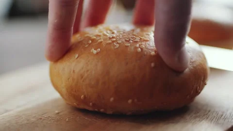 Hamburger Bun Being Sliced in Half by a Kitchen Knife on a Wooden Board 库存影片 331101202