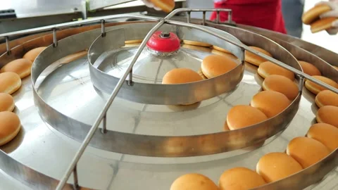 Hamburger buns on the baking line.Hot round delicious burger buns come out of Stock Footage 171892548