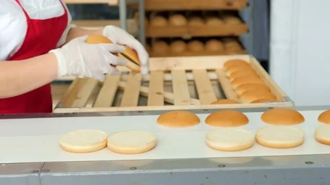 Hamburger buns on the baking line.Hot round delicious burger buns come out of Video stock 171892689