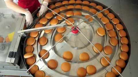 Hamburger buns on the baking line.Hot round delicious burger buns come out of Stock Footage 171892960
