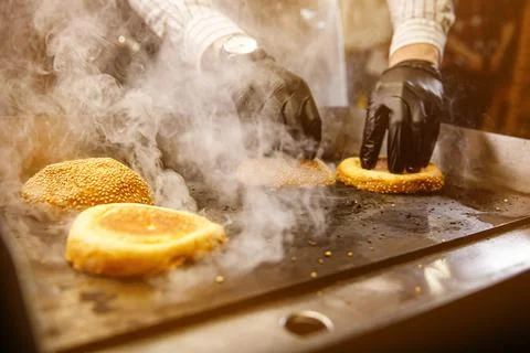 Hamburger buns toasting face down on a hot grill. Stock Photos