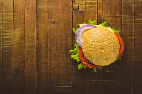 Hamburger with cheese, meat, tomatoes and onions and herbs. On Wooden backgro Stock Photos