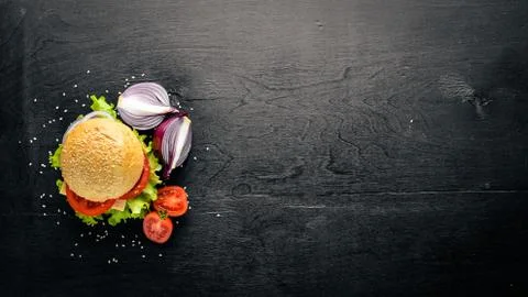 Hamburger with cheese, meat, tomatoes and onions and herbs. On Wooden backgro Stock Photos