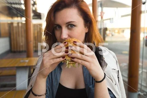 Hamburger close up - Young Woman eating in Fast Food Restaurant - Cheeseburger Stock Photos