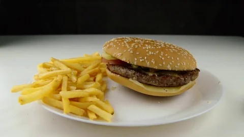 Hamburger down on fried potato chips falling, slow motion, fast food, junk food Stock Footage