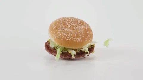 A hamburger falls in slow motion onto a white cyc Stock Footage 70671770
