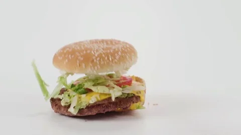 A hamburger falls in slow motion onto a white cyc Stock Footage 70671900