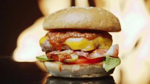 Hamburger with Melted Cheese and Bacon over a Flaming Grill Background 库存影片 331101307