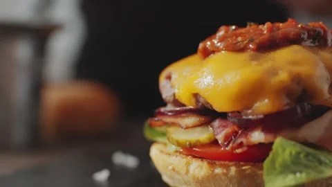 Hamburger Preparation with Melted Cheddar Cheese and Savory Tomato Relish 库存影片 331101302