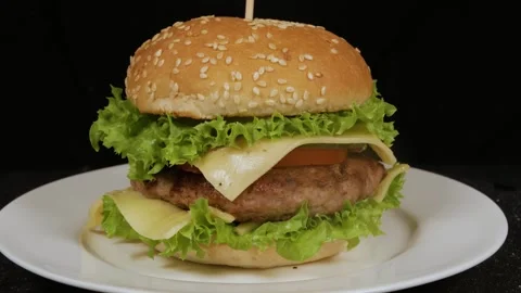 Hamburger rotating on a white plate, isolated on a black background Stock Footage 314329693