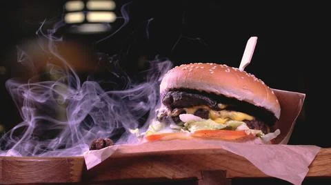 The hamburger is served on a rustic wooden surface and craft paper surrounded Stock Photos