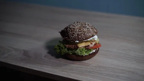 Hamburger stands on a table with a wood texture Stock Footage 128416619
