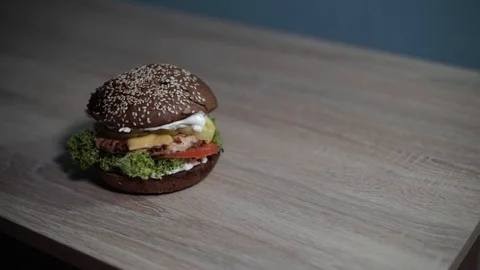 Hamburger stands on a table with a wood texture Video stock 128416679
