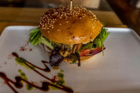 Hamburger in the white plate on a table. Rustic closeup. Stock Photos