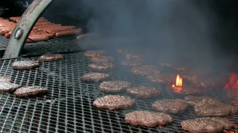 Hamburgers and hot dogs on flaming grill Stock Footage