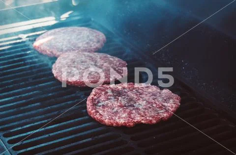 Hamburgers on Grill with Flames Cooked to Perfection Stock Photos