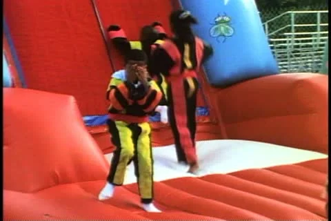 HAMILTON, BERMUDA, 1994, Three black boys jumping on a Velcro trampoline Stock Footage 12260562