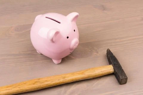 Hammer aiming for pink piggy bank money box on light background. Piggy bank   Фото