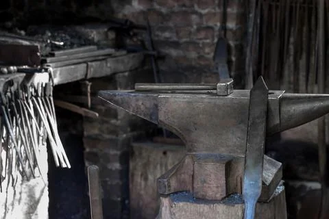 A hammer and a metal object in the forge Stock Photos